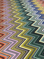 Colorful zigzag pattern upholstery fabric with vibrant stripes in various shades of orange, pink, yellow, green, blue, and purple designed for stylish home decor.