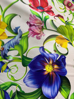 Tropical floral fabric with vibrant multicolored flowers and green leaves on a white background