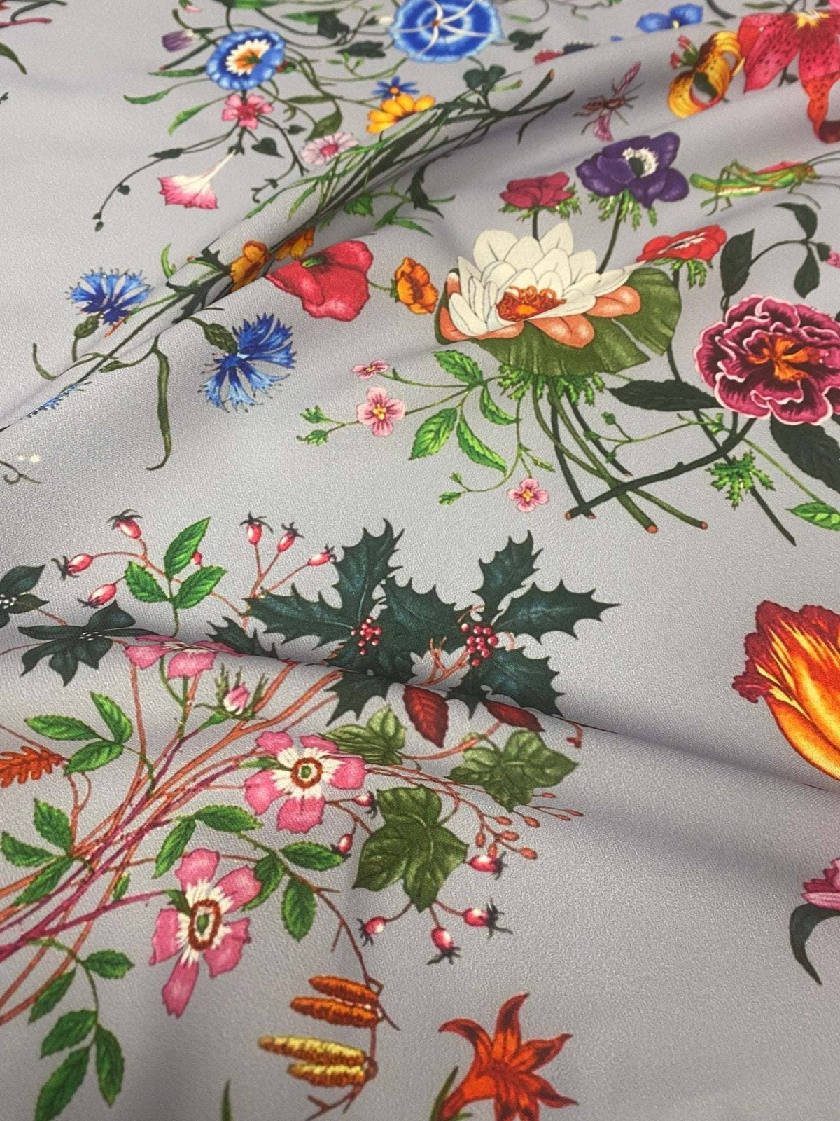 Colorful floral pattern on light grey fabric with various vibrant flowers and green leaves design
