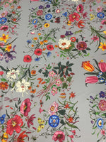Colorful floral pattern fabric on light grey background with vibrant flowers in various colors and styles