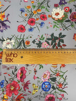 Colorful floral pattern fabric on light grey background with vibrant flowers and greenery, ruler showing fabric width of 150cm