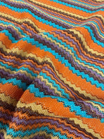 colorful zigzag stripe knit fabric in vibrant orange, blue, yellow, and brown tones with textured pattern