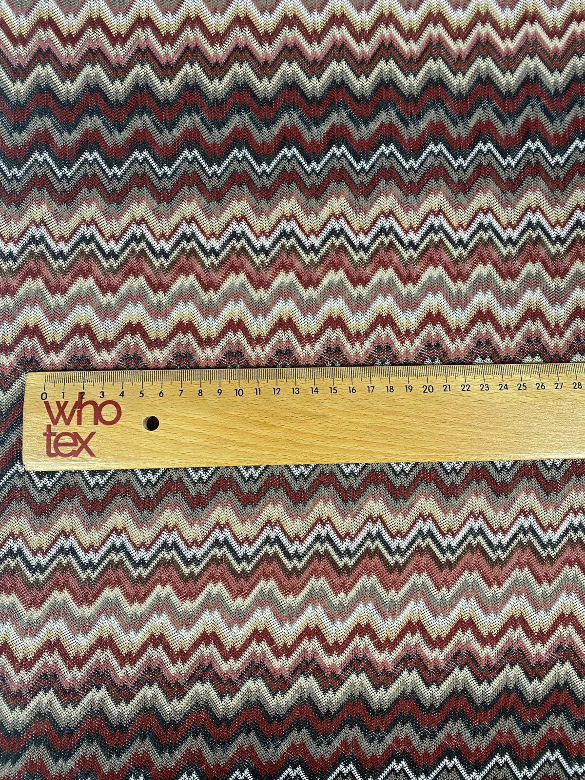Earth tone zigzag woven mesh fabric with multicolor pattern and measuring ruler for scale