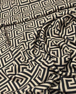 Greek Key Design Fabric in black and beige geometric pattern, 150cm wide, draped on a surface for upholstery and crafts