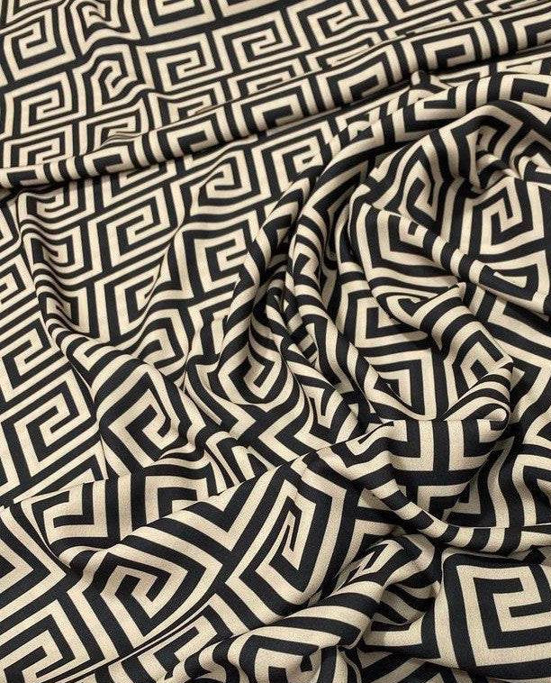 Greek Key Design Fabric in black and beige geometric pattern, 150cm wide, draped on a surface for upholstery and crafts