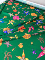 Green fabric with colorful sea shell and starfish pattern for coastal decor and crafting