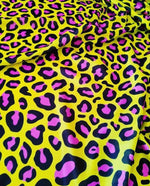 Bright yellow leopard print fabric with bold black and pink animal patterns, ideal for fashion and decor projects.