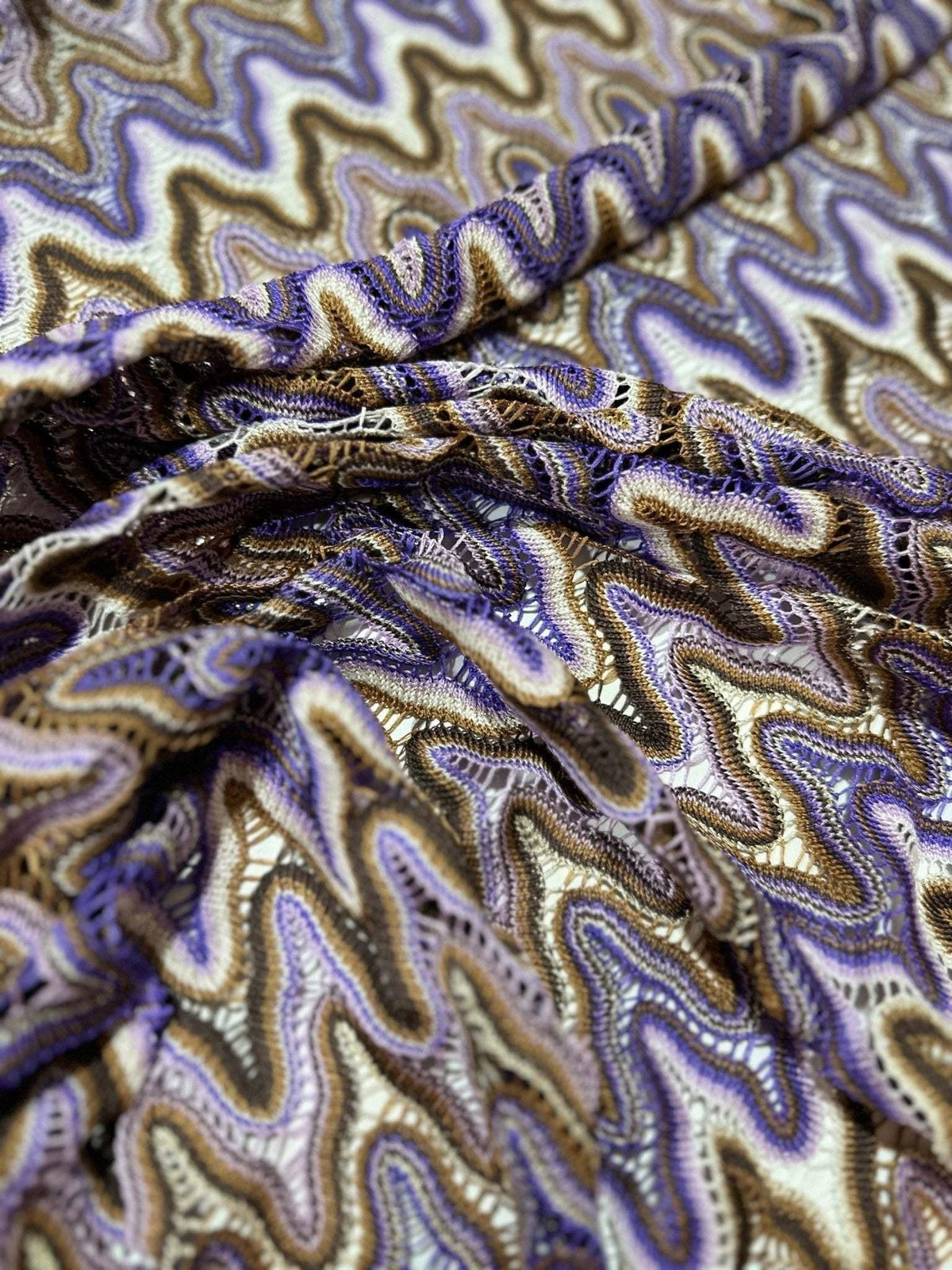 Close-up of purple and brown zigzag knit jersey mesh fabric with intricate textured pattern for versatile sewing projects