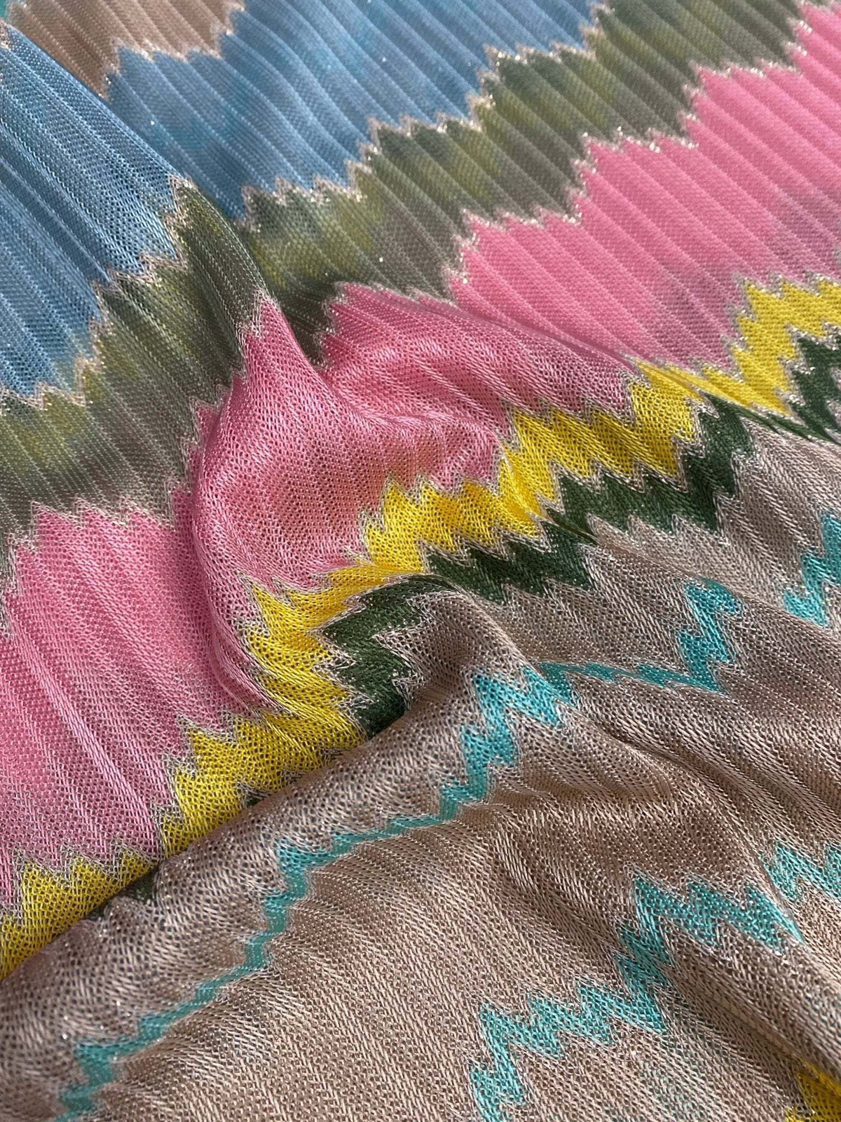 Mesh fabric with multicolor zigzag design in green, pink, yellow, blue, and beige tones with textured knit pattern.