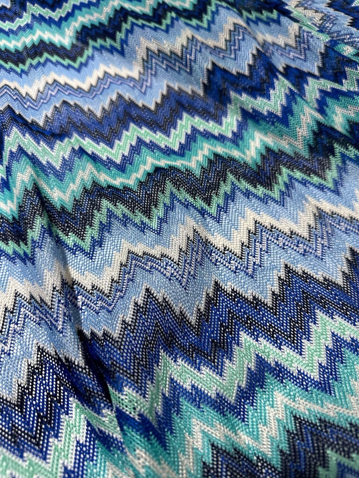 Zigzag knitted mesh fabric with blue and white chevron pattern, soft and stretchy textile for sewing projects