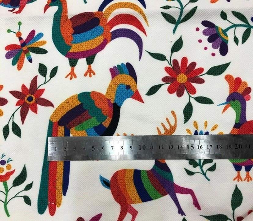 Otomi print outdoor pillow fabric with colorful birds, flowers, and animals on white background and ruler for scale