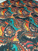 Close-up of multicolor paisley print fabric with vibrant orange, teal, and black patterns