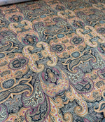 Close-up of black and orange paisley fabric with intricate decorative pattern and vibrant design