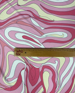 Close-up of pink and yellow psychedelic swirl print fabric with ruler for scale