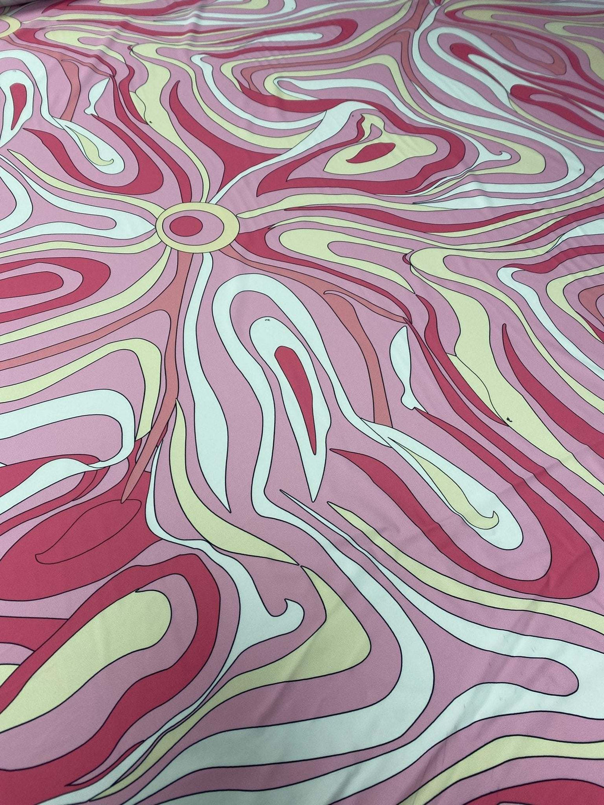 Pink and yellow psychedelic swirl print fabric with vibrant abstract design and smooth texture