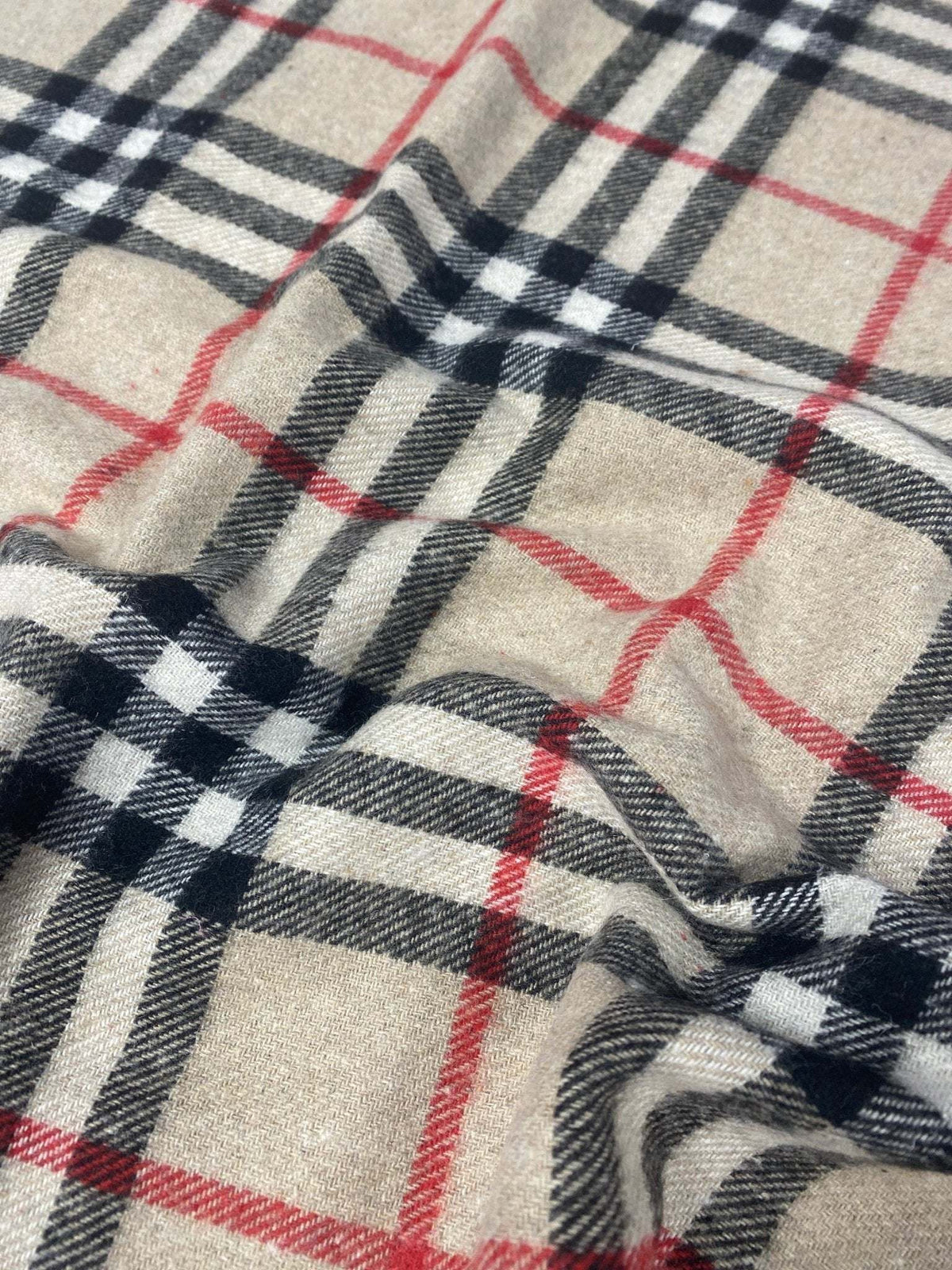 Plaid woolen fabric with beige background and black, white, and red check pattern, suitable for jackets and coats.