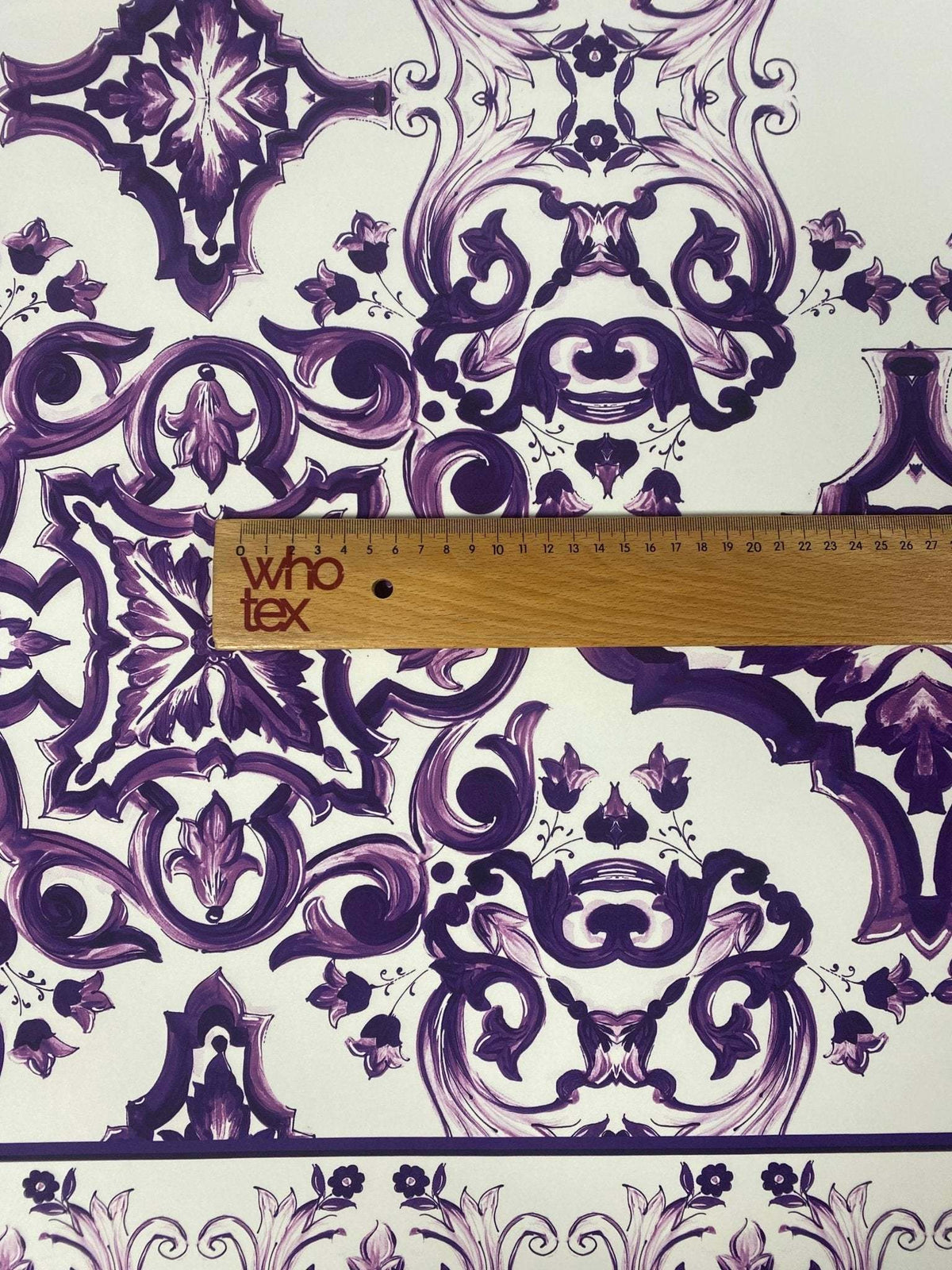 Purple Baroque floral pattern fabric with intricate decorative designs and ruler for scale