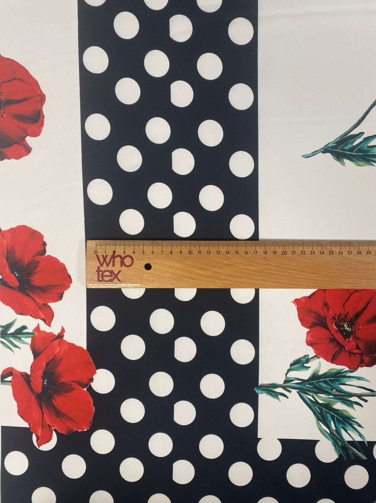 Red poppy floral fabric with black and white polka dot border and ruler showing fabric width