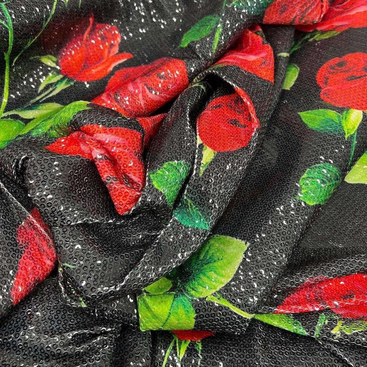 Close-up of black sequin fabric with vibrant red rose pattern and green leaves, featuring two-way stretch and glittering texture