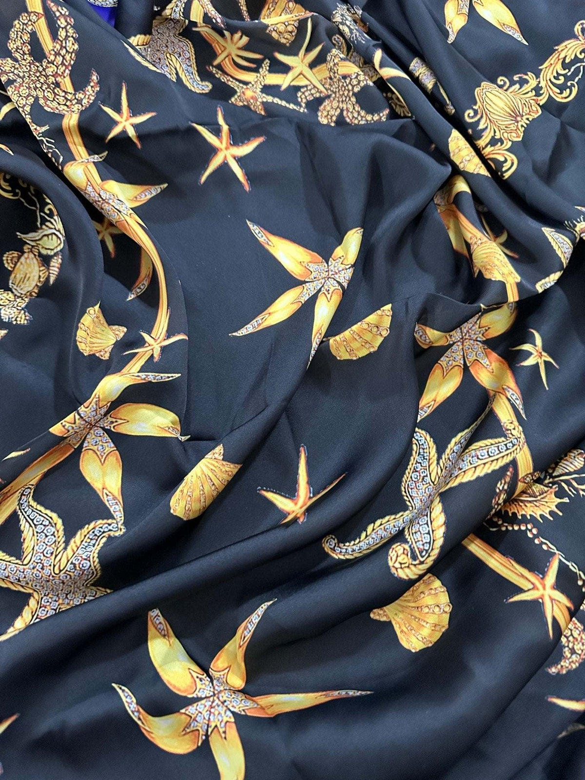 Black luxury fabric with yellow sea shell and starfish pattern on rich black background