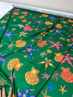 Green fabric with colorful sea shell and starfish pattern for coastal decor and crafting projects