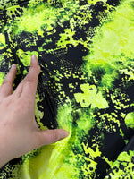 Neon green spandex fabric with black abstract pattern, stretchy texture shown with hand stretching material