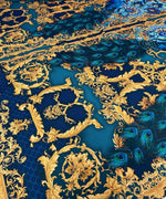 Vintage peacock pattern fabric with intricate gold and blue designs and vibrant peacock feathers.