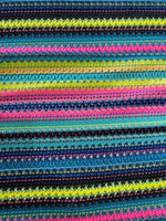 Colorful zigzag knit jersey fabric with vibrant stripes in black, yellow, pink, and blue, ideal for fashion garments